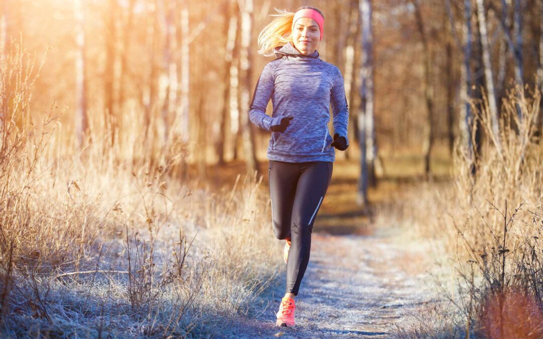 A woman runs on a trail in cold weather.